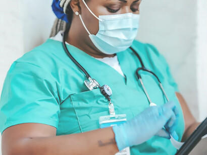 A mask-clad, accomplished doctor carefully studies the chart in her hand, exemplifying professionalism and dedication