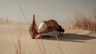A shared reverence, Karlien folding into the dunes beside ‘Diatom Bokeh’ from the Epiphanic series collaboration with Reticence Studio, photographed by Driaan Claassen
