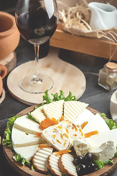 The exquisite pairing of a cheese plate and a glass of red wine, featuring Pecorino Romano cheese and savory Guanciale in a captivating front view shot, perfect for indulgent dining scenes