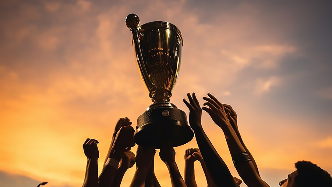 Celebrate victory with a compelling image of hands lifting a football cup, symbolizing triumph and success in soccer championships