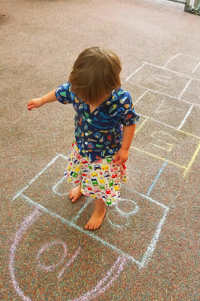 The young girl leaps with joy across the hopscotch grid, embodying the same playful spirit and determination that made this childhood game a beloved tradition for so many