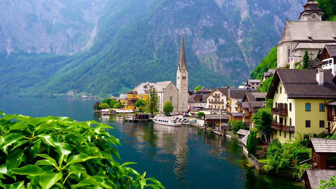 Scenic white and brown concrete building nestled near a serene body of water in Hallstatt, Austria, offering an idyllic outdoor retreat amidst nature