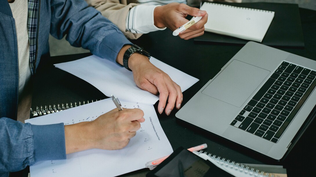 People working on laptops and paper to complete university work