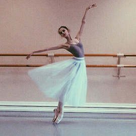 A ballet dancer gracefully moves within a pink-walled room