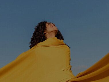 The essence of freedom and authenticity as a woman holds a yellow cloth amidst nature, embodying liberation in this captivating image