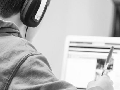 A boy is listening with headphones, doing homework online