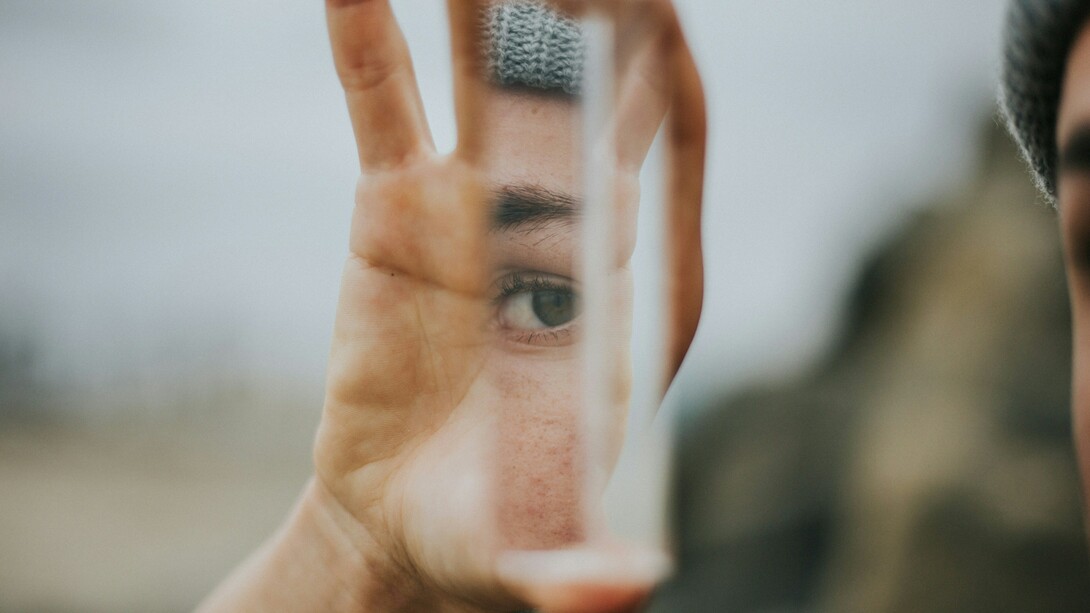 A woman's eye, reflected on a glass shard she's holding