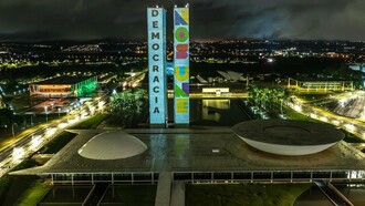 O Congresso Nacional do Brasil recebe a projeção da ação "Democracia Inabalada", que exibiu as mensagens "Democracia" e "Nos Une" nas torres do parlamento em memória de um ano dos ataques de 8 de janeiro de 2023. Em um cenário de incertezas políticas, o texto discute os desafios para preservar e renovar a democracia. Palácio do Congresso Nacional, Praça dos Três Poderes, Brasília - DF - Brasil