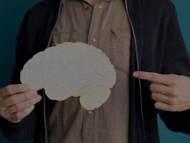 The close-up image of someone pointing at a paper brain emphasizes critical insights into maintaining brain health and managing stroke