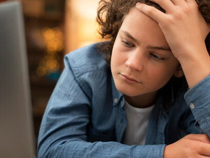 A young man appearing worried while scrolling through his phone, reflecting the emotional impact of consuming negative news