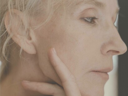 A woman gently stroking her skin as she pinpoints the rapidly ageing areas