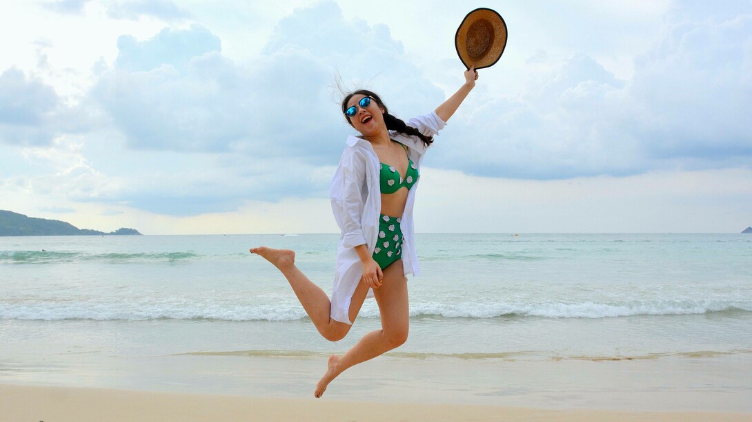 A woman skipping and jumping on the beach expressing her happiness