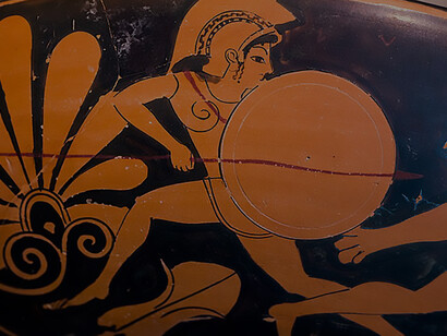 Details of the Oltos ARV 62 85 artwork, depicting a young warrior adorning his armor amidst the inscription 'Memnon Kalos,' the epic battle of Heracles against three Amazons, painted with masterful precision and attributed to the talented artist from Athens