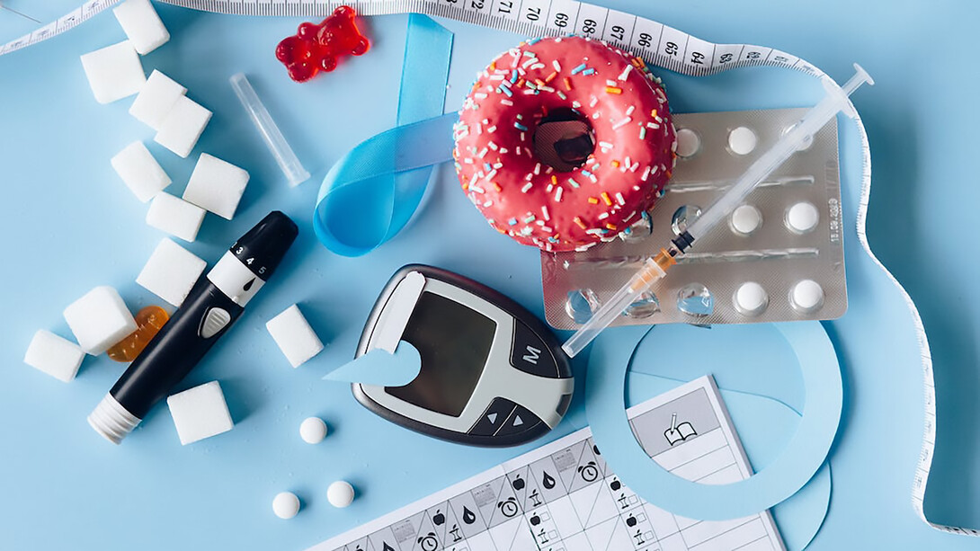 Glucometer, donut, and tape measure on blue background