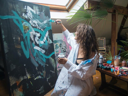 An artist, a woman, deeply immersed in her work, applying paint to a canvas