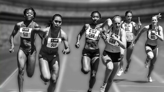 Women athletes running in a daytime race as fans cheer from the stadium