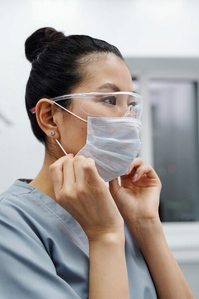 A nurse wearing a mask and protective glasses