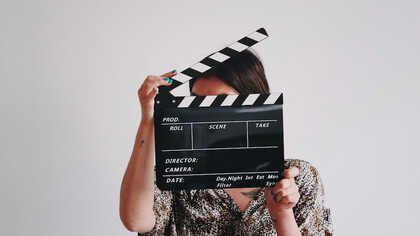 A woman holding a clapper over her face