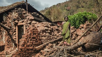 Woman standing near a house destroyed by an earthquake in India