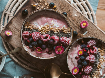 Two bows of yogurt with different toppings: raspberries,açaí and seeds
