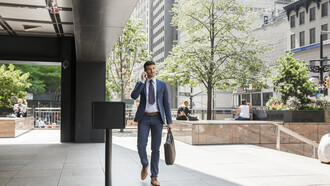 Businessman walking away from the office while speaking on the phone