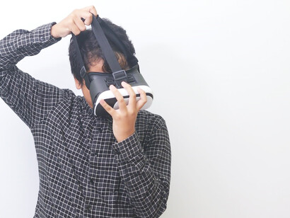 An Asian man immerses himself in a world of virtual reality, donning VR glasses and engaging in captivating gaming experiences