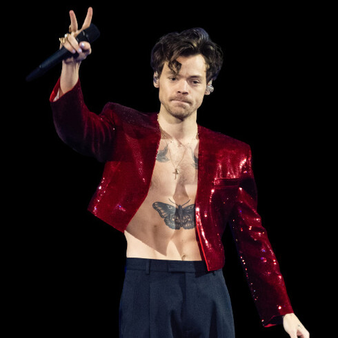 No palco, o cantor Harry Styles usa uma calça de alfaitaria coz alto e um blazer de paetês