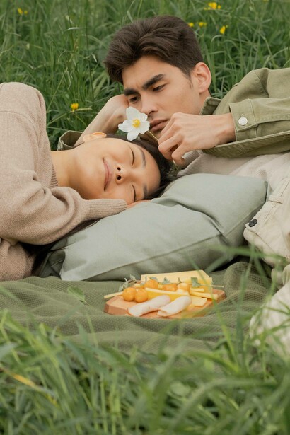 Woman takes a nap as man smells flower