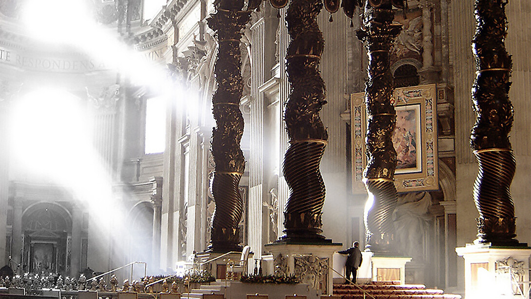 The ancient Solomonic columns mounted above the balcony, positioned in the upper-right background against the wall in St. Peter's Basilica, Vatican City, Italy