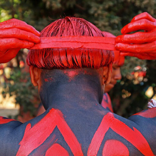 Indígena em ritual tradicional no Parque do Xingu (Mato Grosso) usa urucum para pintar o corpo. Foto de David Ribas