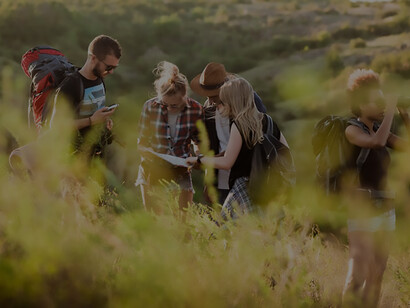 Adventurous young friends, each with a backpack, savoring a scenic view as they explore a canyon, capturing the spirit of camaraderie and travel
