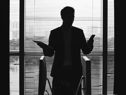 Dark silhouettes of a man and woman in business attire standing by a window in a modern office, symbolizing professionalism and corporate dynamics