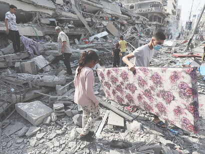 Palestinians inspect the ruins of Aklouk Tower destroyed in Israeli airstrikes in Gaza City on October 8, 2023