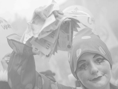 A mime waving around monopoly money as a commentary against the super-rich and their extravagant waste