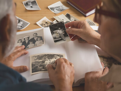 A couple, engrossed in cherished memories, gracefully peruses a photo album brimming with images capturing the essence of their ancestors and the tapestry of their family legacy