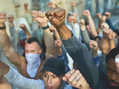 A close-up view reveals a fervent crowd of protesters raising their arms in a powerful demonstration on the streets