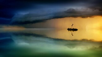 Entre o ouro do entardecer e o azul profundo da tormenta, uma ilha mínima resiste no silêncio do mar, duplicada pelo reflexo que a torna quase irreal. A cena evoca o fascínio ancestral pelas ilhas que surgem e desaparecem, habitando tanto os mapas quanto o imaginário, lugares onde o mistério persiste e a história parece, por instantes, suspensa