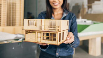 Smiling African American woman holding a model of a portable house