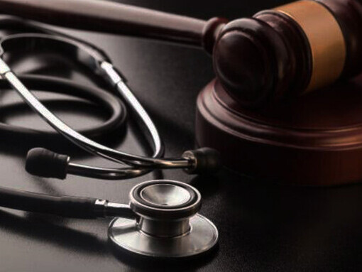 A gavel and stethoscope lie on a wooden table, representing the intersection of legal and ethical challenges in addressing healthcare inequality