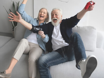 An elder couple immersed in playful interaction with a gaming console, challenging stereotypes and showcasing the timeless joy of shared digital adventures