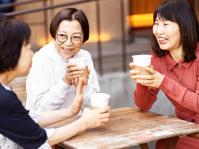 Middle-aged Korean women enjoy a cheerful time together at a coffee shop, laughing and chatting happily over drinks