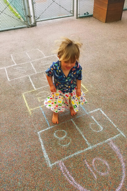 With each jump on the hopscotch squares, the young girl experiences the thrill and camaraderie that come with this timeless game, reconnecting with the simple pleasures of childhood