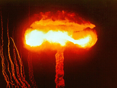 The massive explosion from a 1957 Nevada nuclear test symbolises the ongoing peril of nuclear arms, underscoring a pervasive mistrust that drives nations to retain these destructive weapons