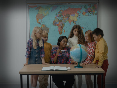 A female teacher pointing to the earth globe showing students the countries