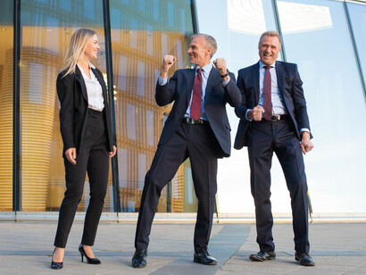Cheerful business professionals celebrating their success together in front of a modern glass office building
