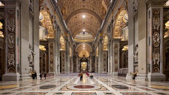 La navata centrale della Basilica di San Pietro si apre come un immenso spazio solenne e luminoso, scandito da colossali pilastri e ornato da marmi policromi e mosaici dorati, che guidano lo sguardo verso l’altare papale. Foto di Nate Bergin. Basilica di San Pietro, Città del Vaticano