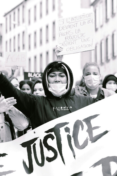 A grayscale photo of a woman holding a "Black Lives Matter" sign in Brest, France