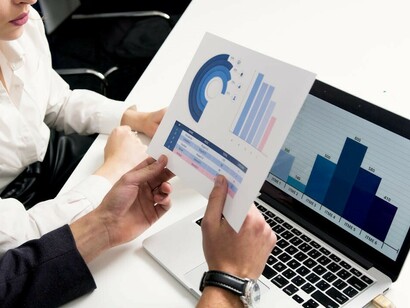 Economists examining data with a screen displaying multiple graphs in front of them