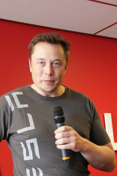 Elon Musk during a press conference; his efforts with Tesla, OpenAI, and Neuralink demonstrate a commitment to pushing the boundaries of innovation