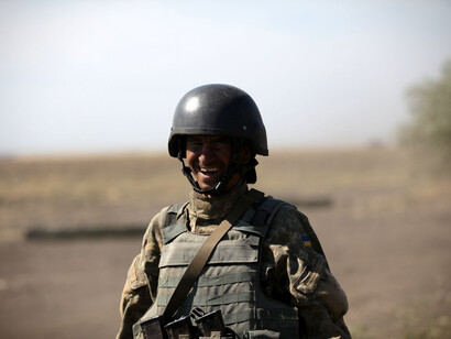 A male soldier on the field, smiling at the camera